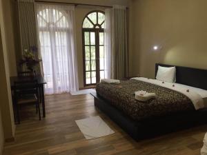 a bedroom with a bed and a desk and windows at Panorama Green View Hotel Nuwara Eliya in Nuwara Eliya