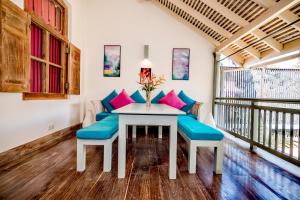 a dining room with a white table and blue cushions at Small House Boutique Guest House in Galle