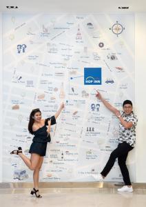 a man and a woman standing in front of a wall at Hop Inn Hotel Tomas Morato Quezon City in Manila