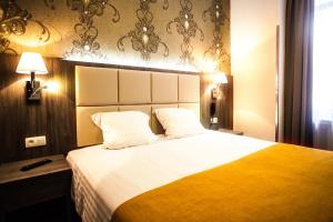 een hotelkamer met een groot bed met wit en geel bij Dansaert Hotel in Brussel