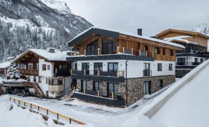 un edificio en la nieve con una montaña en el fondo en A CASA Rubin Chalet & Studio Resort, en Sölden