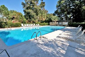 a swimming pool with white chairs and a swimming pool at Night Heron 35 in Hilton Head Island