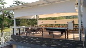una terraza cubierta con mesa de ping pong y sillas en One-8 Premium Villa, en Dayu