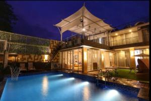 a swimming pool in front of a house at night at One-8 Premium Villa in Dayu