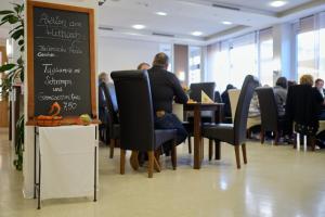 a man sitting at a table in a restaurant with a chalkboard at Gästehaus Schumm in Murrhardt