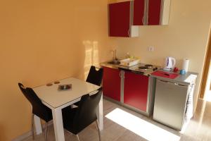 a small kitchen with a table and a small kitchen with red cabinets at Apartments Leon Nin in Nin