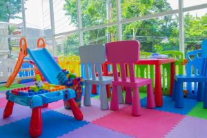 una sala de juegos de colores vivos con mesas y sillas coloridas en Radja Art and Boutique Hotel Simpang Lima, en Semarang