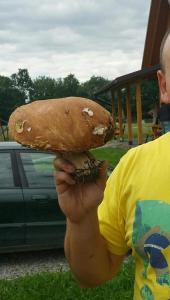 a man holding a large sandwich in his hand at Domki całoroczne Bieszczady Panasiewiczówka in Odrzechowa