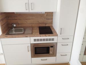 uma pequena cozinha com armários brancos e um micro-ondas em Munich Apartment em Munique