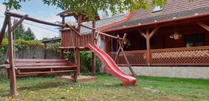 a playground with a slide and a bench in front of a house at Alexandra Vendégház in Abádszalók