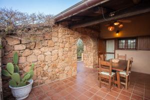 a patio with a table and chairs and a stone wall at Villa Alberto - Klodge in Porto San Paolo