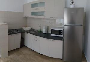 a kitchen with a stainless steel refrigerator and white cabinets at Pensiunea Denis in Cârțișoara