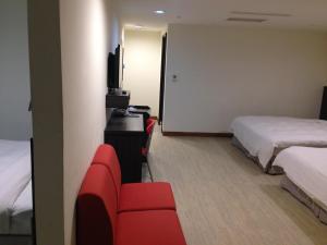 Habitación de hotel con 2 camas y sofá rojo en Big Bear Hotel, en Kaohsiung