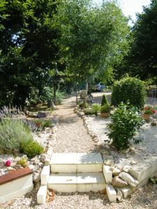 The Lodge في Les Dognons: حديقة لها مسار حجري مع الزهور والأشجار
