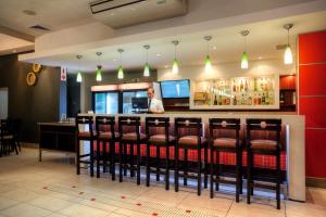 a bar with chairs and a man behind a counter at Hotel Osner in East London