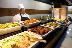 a chef standing behind a buffet line of food at Hotel Osner in East London