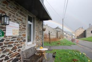 a bench next to a building with a rainbow in the background at B&B Le Renard Dormant in Opont