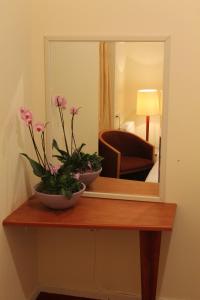 a mirror on top of a wooden table with flowers at Hotel Isis in Amsterdam