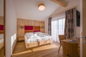 a bedroom with a bed and a desk and a window at Appartementhaus Adlerblick in Mayrhofen