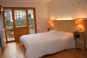 ein Schlafzimmer mit einem großen weißen Bett und einem Balkon in der Unterkunft Hôtel Le Chalet in Ax-les-Thermes