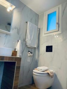 a white bathroom with a toilet and a window at Villa Blue Apartments in Agia Triada