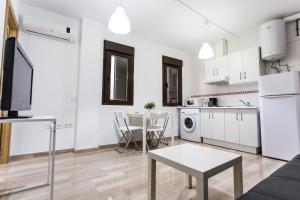cocina y sala de estar con armarios blancos y mesa en C&V Apartamentos - Horno de Marina, en Granada