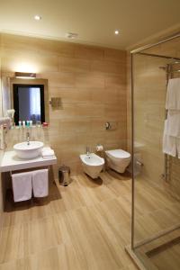 ein Badezimmer mit zwei Waschbecken, einer Dusche und einem WC in der Unterkunft Pushcha Congress Hotel in Kiew