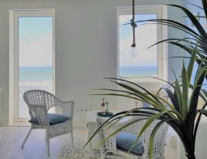 a chair and a plant in a room with windows at The Shore @ BaíaBeach - Waterfront in Espinho