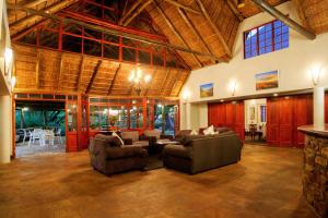 a living room filled with furniture and a large window at Hogsback Arminel Hotel in Hogsback
