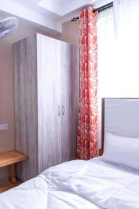 a bedroom with a white bed and a wooden cabinet at Serene Homes in Mombasa