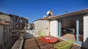 um pátio com uma mesa e cadeiras numa varanda em L'Escalier Rouge em Arles