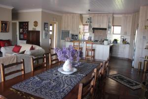 una cocina y una sala de estar con una mesa con flores. en Traveller's Rest, Reebok en Mossel Bay