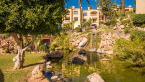 a pond in a garden with a building in the background at Macdonald Doña Lola Resort in La Cala de Mijas