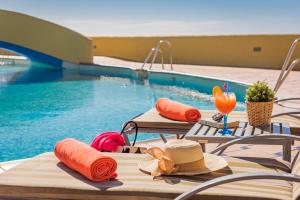 a group of tables with hats and drinks next to a swimming pool at Macdonald Doña Lola Resort in La Cala de Mijas