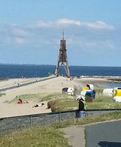 um homem ao lado de uma praia com um moinho de vento em Ferienwohnung Nordwind em Cuxhaven