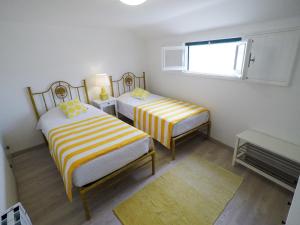 エリセイラにあるCasas do Norteのベッドルーム1室(黄色と白のシーツを使用したベッド2台付)