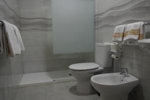 a white toilet sitting next to a sink in a bathroom at Hotel Valencia in Las Palmas de Gran Canaria