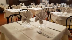 a group of tables with white table linen and silverware at Hotel Galassia in Prato Nevoso