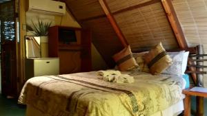 a bedroom with a bed with two stuffed animals on it at Elephant Trail Guesthouse and Backpackers in Kasane