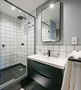 a bathroom with a sink, mirror, and bathtub at The Onyx Apartment Hotel in Cape Town