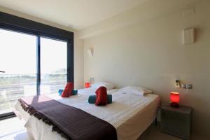 1 dormitorio con 2 camas con almohadas rojas y ventana en Villa Wivine, en Moraira