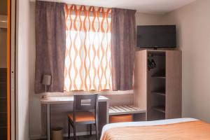 um quarto com uma cama, uma secretária e uma janela em Logis Hôtel Les Voyageurs em Lezoux