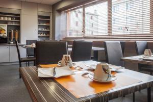a dining room with tables and chairs with cups and napkins at Logis Hôtel Les Voyageurs in Lezoux