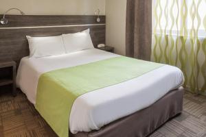 Logis Hôtel Les Voyageurs في Lezoux: غرفة نوم بسرير كبير مع بطانية خضراء