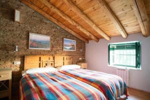 1 dormitorio con 1 cama con una manta colorida en Casa de los Curas, chimenea 2 Hab 4 Pers Max, en Puerto de la Laja