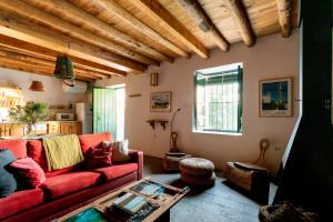 sala de estar con sofá rojo y mesa en Casa de los Curas, chimenea 2 Hab 4 Pers Max, en Puerto de la Laja