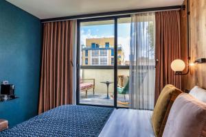 Schlafzimmer mit einem Bett und Blick auf einen Balkon in der Unterkunft Fabric Hotel - an Atlas Boutique Hotel in Tel Aviv