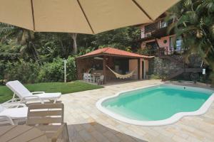 una piscina con due sedie e un ombrellone di CASA MARAVILHOSA à BEIRA MAR EM ANGRA DOS REIS ad Angra dos Reis