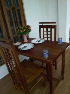 a wooden table and chairs with plates and glasses on it at Sumudu Villa in Hikkaduwa