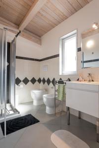 ein Badezimmer mit 2 WCs, einem Waschbecken und einem Spiegel in der Unterkunft Casa Zefiro in Pozzallo